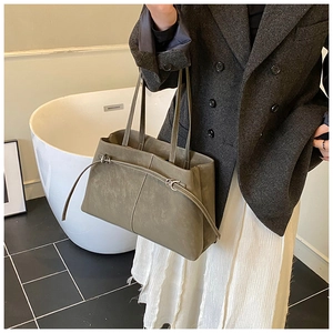 Detail of grey-green matte bucket tote bag with decorative straps and metal buckle