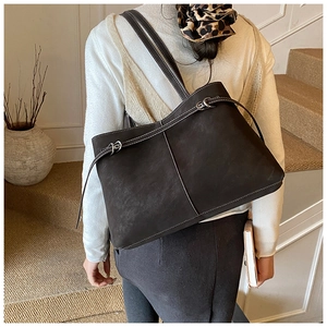 Detail of dark brown tote bag with white contrast stitching and long thin strap