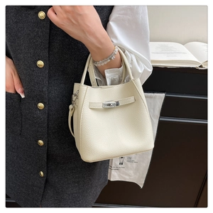 Detail of cream bucket bag in lychee leather featuring silver twist lock and handle