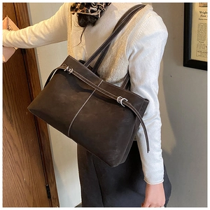 Detail of vintage brown suede tote bag with contrast stitching and decorative buckles