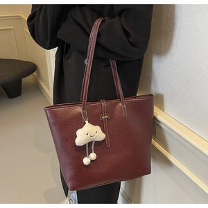 Macro shot of large burgundy tote bag with textured leather and white cloud charm