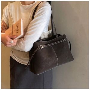 Detail of dark brown suede tote bag featuring contrast stitching and side buckle strap