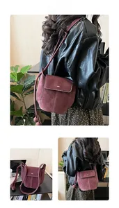 Detail of burgundy suede bucket bag with decorative twin ball charms and stitching
