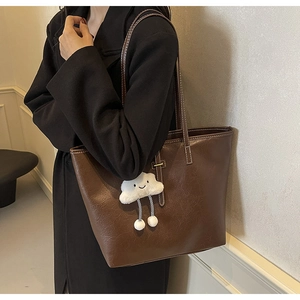 Detailed macro view of brown PU leather tote bag with soft plush cloud charm