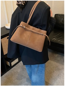 Detail shot of caramel suede tote bag with decorative leather strap and metal buckle