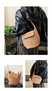 Detail of brown suede shoulder bag with contrast stitching and ball charm details