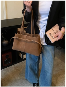 Detail view of large brown suede tote bag featuring metallic buckle and long shoulder straps