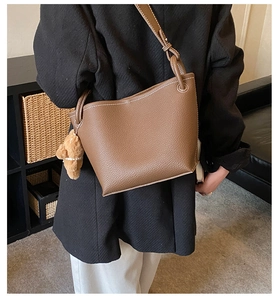 Détail du sac seau marron montrant le cuir grainé et les surpiqûres blanches