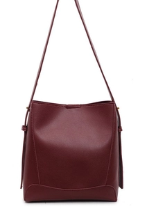 Minimalist burgundy faux leather bucket bag with wide strap and pebble grain texture