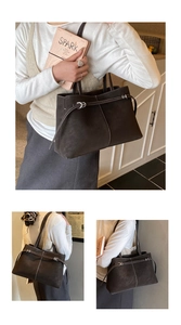 Detail of dark brown suede tote bag with white contrast stitching and silver hardware