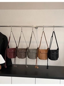 Close-up of five vintage crossbody bags in various colors on a silver metal hanger