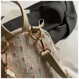 Macro detail of elegant tweed fabric texture with gold metal hardware on chic backpack