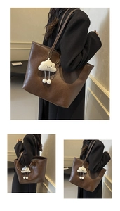 Detail of dark brown faux leather tote bag with a cute white plush cloud charm accessory