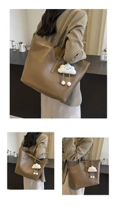 Detail view of brown leather tote bag with long straps and white plush cloud charm