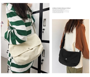 Detail view of large canvas messenger bags in black and beige with adjustable straps