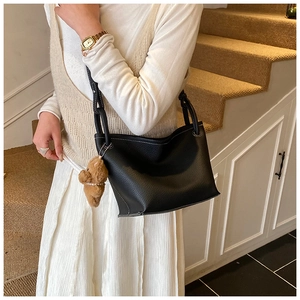 Détail du sac seau noir en cuir grainé avec coutures contrastées et breloque ourson