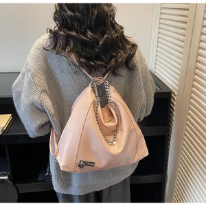 Pink leather hobo bag with silver chain strap shown as a functional backpack on a model