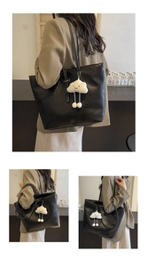Detail of black pebbled PU leather tote bag with white plush cloud charm and long strap
