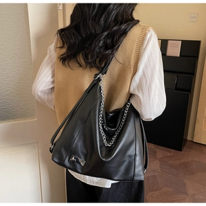 Close-up of large black PU leather tote bag with silver chain and heart pendant details