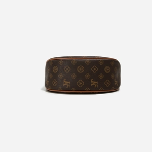 Macro detail of curved bottom and monogram pattern on brown faux leather crossbody bag