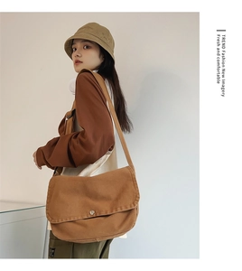Close-up of large brown canvas crossbody tote bag with flap and metal snap closure
