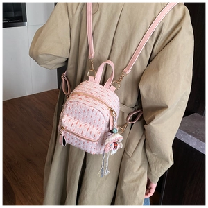 Detail of pink tweed small backpack featuring gold hardware and elegant fringe charm