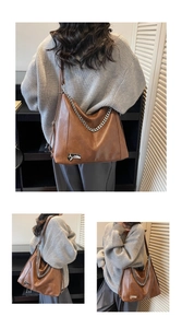 Detail of brown vintage faux leather tote bag with silver chain strap and metal plate
