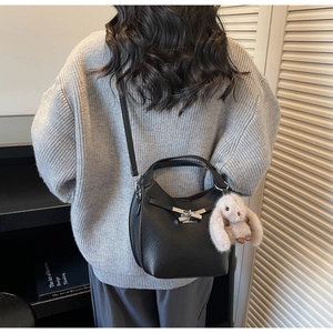 Detail of black lychee grain leather crossbody bag with silver buckle and plush rabbit charm