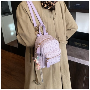 Detail of light purple tweed mini backpack with gold hardware and woven charm accessory