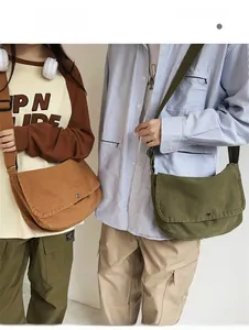 Detail of tan and olive canvas crossbody bags with adjustable straps and button closure