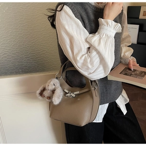 Close-up of litchi grain leather texture and metal lock with a cute plush bunny charm