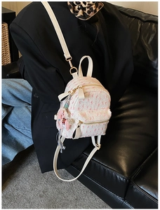 Detail of a white and pink tweed mini backpack with a decorative horse charm