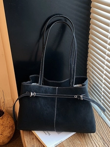 Retro black tote bag with white stitching and decorative buckle on a minimalist desk