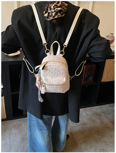 Rear view of a mini pink tweed backpack with heart pendant and golden hardware details
