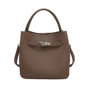 Brown lychee leather bucket bag with top handle and metal lock on white background