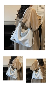 Detailed close-up of a white large leather tote bag with silver chain and metal clasp