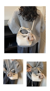 Close-up of white lychee grain leather handbag featuring a silver twist lock and bunny charm