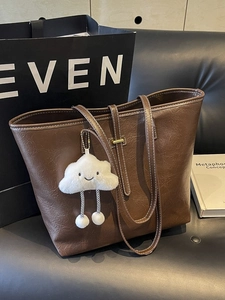 Vintage dark brown tote bag with white contrast stitching and a plush cloud charm accessory