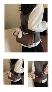 Detail of dark brown lychee leather handbag with silver twist lock and bunny charm