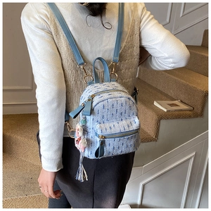 Macro detail of light blue tweed mini backpack showing woven fabric and leather straps