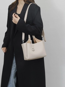 Elegante borsa tote beige in pelle martellata indossata con un outfit da ufficio