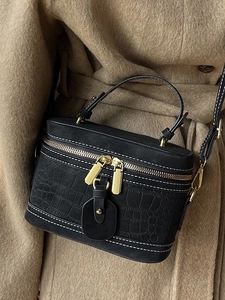 Schwarze Box-Tasche mit Krokodilprägung, weißen Nähten und Goldbeschlägen am Model