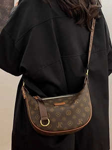 Brown monogram dumpling bag with adjustable shoulder strap worn by a female model
