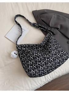 Close-up of black and white floral canvas tote bag with a white plush ball keychain