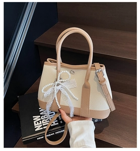 Detail of lychee pattern leather bag with pearl bow and lace charm on wooden stairs
