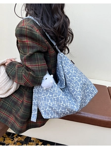 Detail of blue textured canvas tote bag with plush charm on minimalist autumn background
