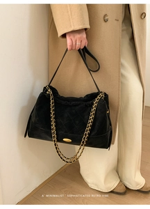 Detailed shot of black quilted suede tote with gold hardware and a chain strap