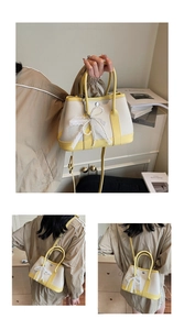 Detail view of canvas tote bag with yellow leather trim and pearl bow charm accessory