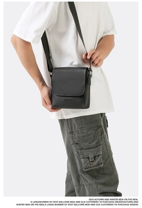 Detail view of the black leather texture and brand embossing on the crossbody bag