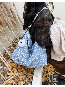 Side view of large tote bag in grey-blue stone pattern with plush white ball charm